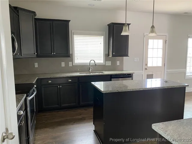 a kitchen with granite countertop a sink a stove and cabinets