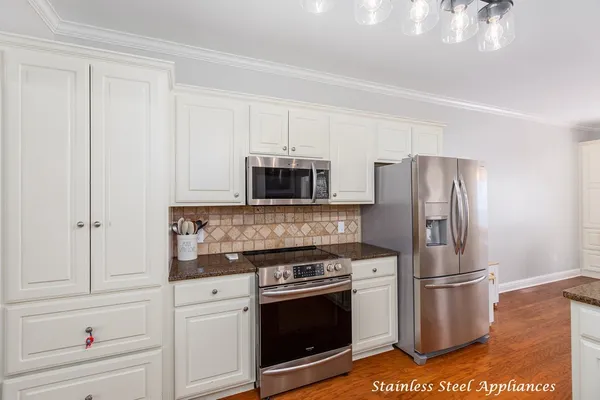 a kitchen with stainless steel appliances white cabinets and a stove top oven