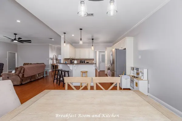 a living room with stainless steel appliances kitchen island granite countertop furniture a rug kitchen view and a chandelier
