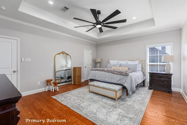 a spacious bedroom with a bed a dresser and a chandelier