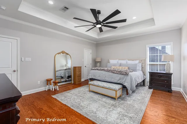 a spacious bedroom with a bed a dresser and a chandelier
