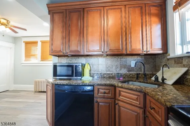 a kitchen with granite countertop a sink a window and cabinets