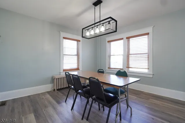 a dining room with wooden floor a chandelier a wooden table and chairs