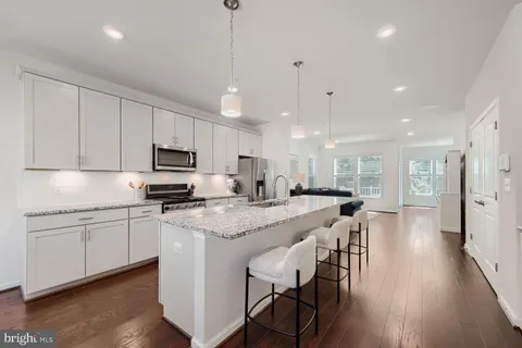 a kitchen with stainless steel appliances granite countertop a sink a stove a refrigerator a dining table chairs and chairs