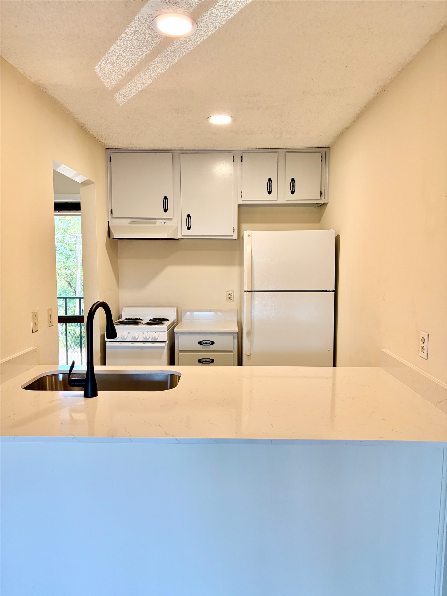630 Maiden Lane, Unit G Austin, TX 78705 - Photo 2 of 3 Kitchen featuring white cabinetry, a built-in sink with a matte black faucet, and light-toned countertops