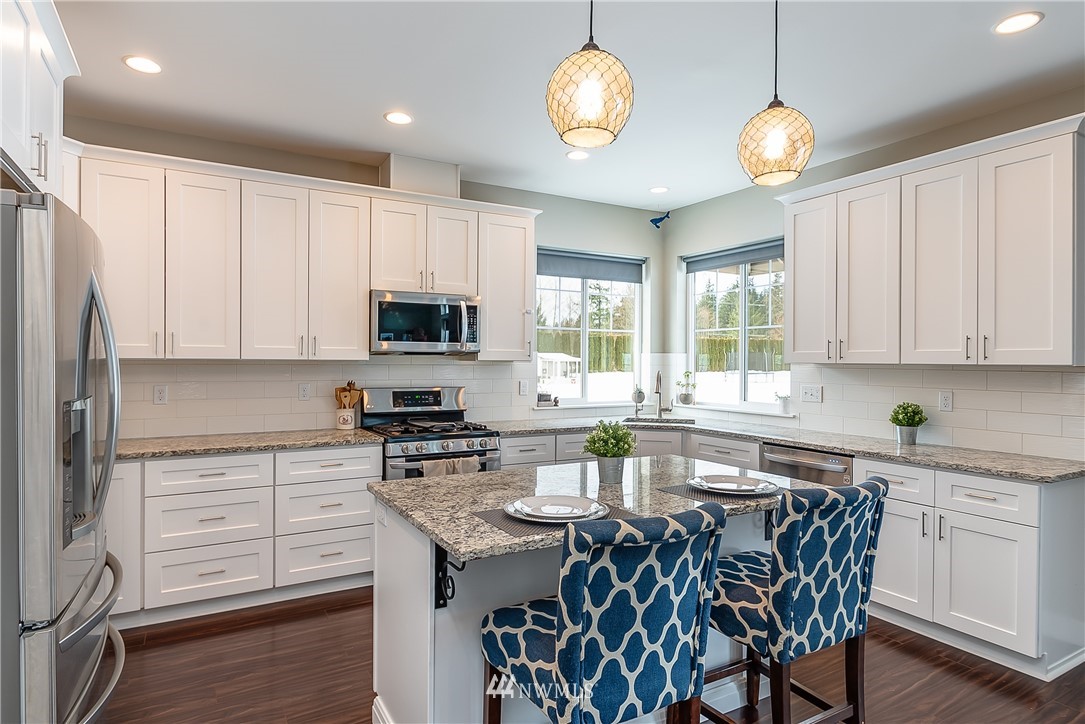3519 McGee Road Blaine, WA 98230 - Photo 12 of 40 a kitchen with stainless steel appliances granite countertop a stove top oven a sink dishwasher a dining table and chairs with wooden floor