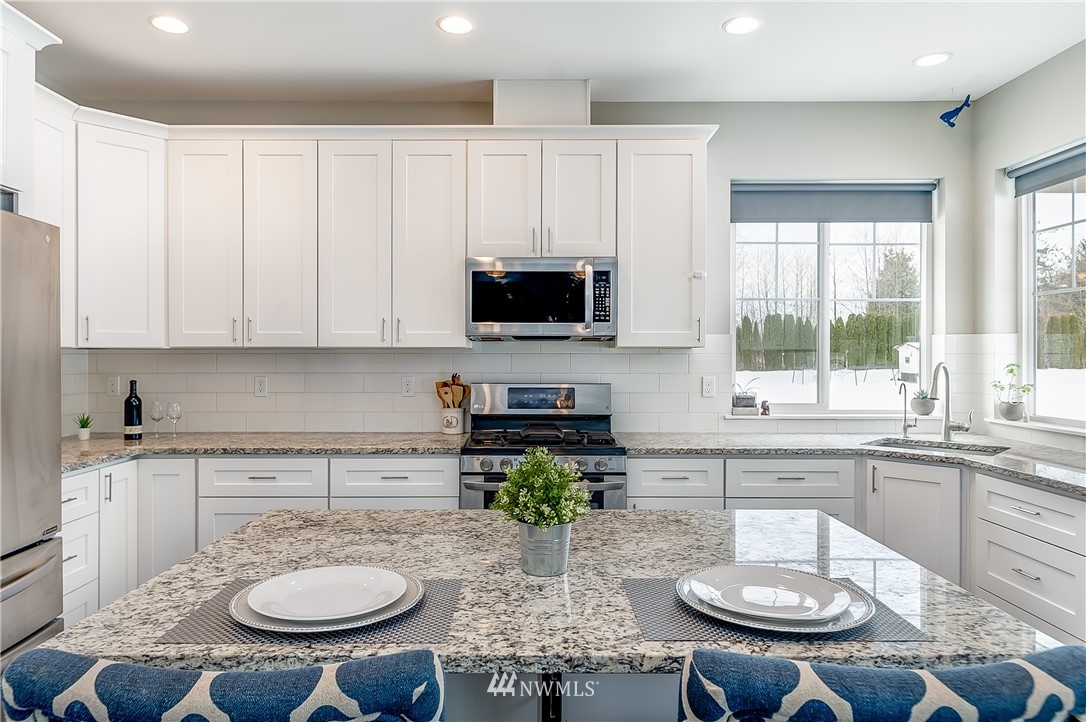3519 McGee Road Blaine, WA 98230 - Photo 13 of 40 a kitchen with stainless steel appliances granite countertop a stove a sink a microwave a dining table and chairs