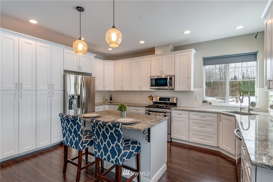 3519 McGee Road Blaine, WA 98230 - Photo 16 of 40 a kitchen with stainless steel appliances granite countertop a stove top oven a refrigerator a sink and a dining table with wooden floor