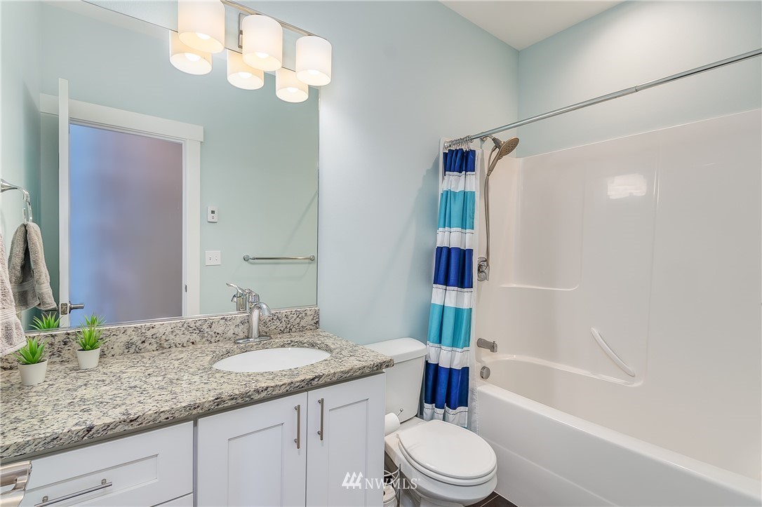 3519 McGee Road Blaine, WA 98230 - Photo 28 of 40 a bathroom with a granite countertop sink toilet a mirror a bathtub and shower
