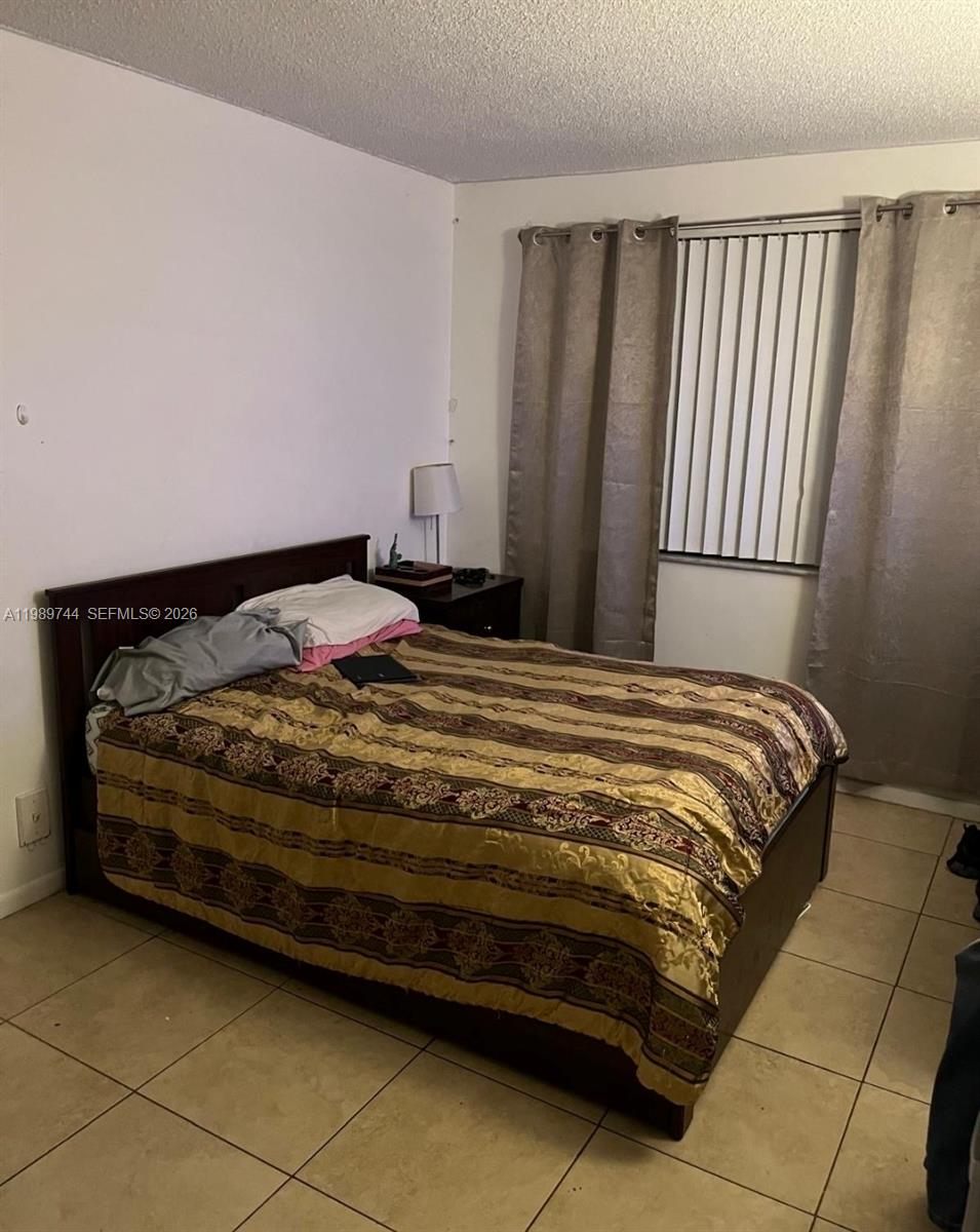 8761 Wiles Road, Unit 206 Coral Springs, FL 33067 - Photo 11 of 16 a bedroom with a bed and a window