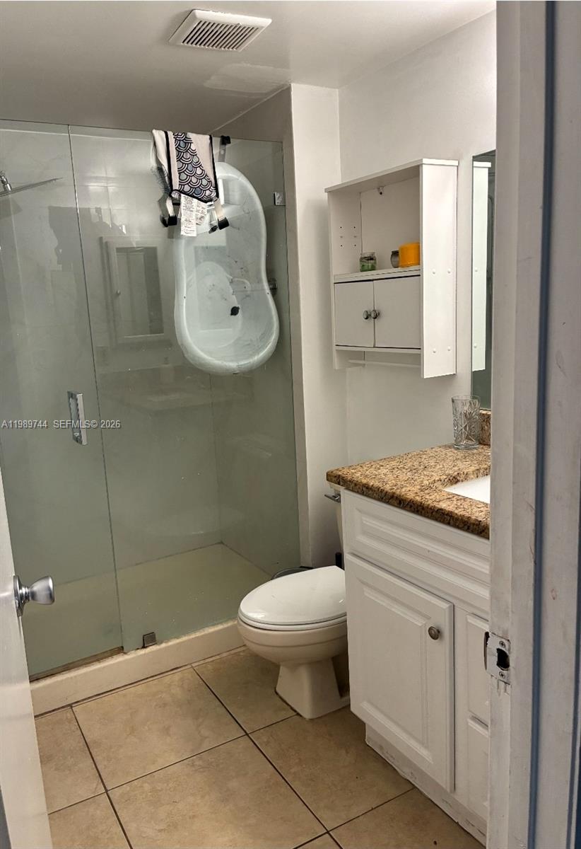 8761 Wiles Road, Unit 206 Coral Springs, FL 33067 - Photo 13 of 16 a bathroom with a granite countertop sink a toilet and a mirror