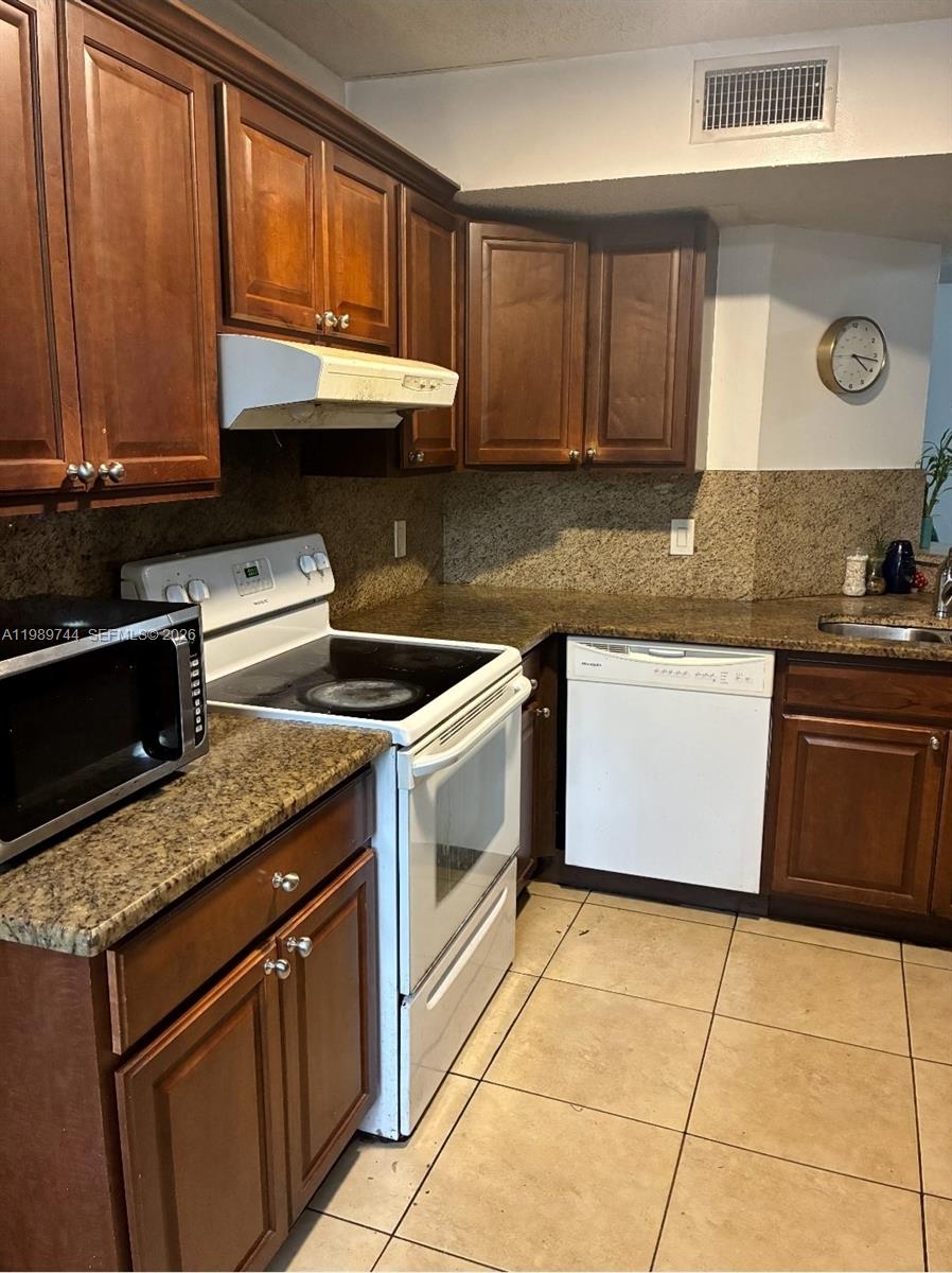 8761 Wiles Road, Unit 206 Coral Springs, FL 33067 - Photo 9 of 16 a kitchen with stainless steel appliances granite countertop a stove a sink and a microwave