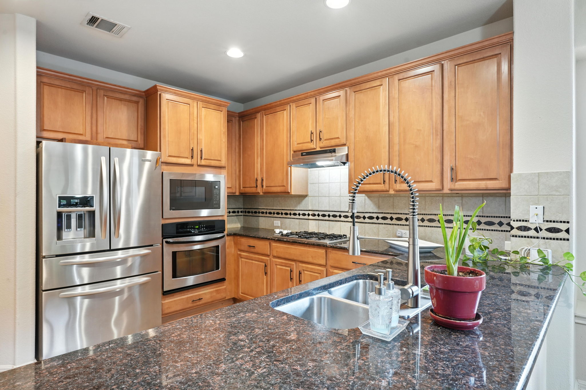 1802 Misty Ridge Leander, TX 78641 - Photo 11 of 39 Kitchen with appliances with stainless steel finishes, under cabinet range hood, recessed lighting, dark stone counters, and backsplash