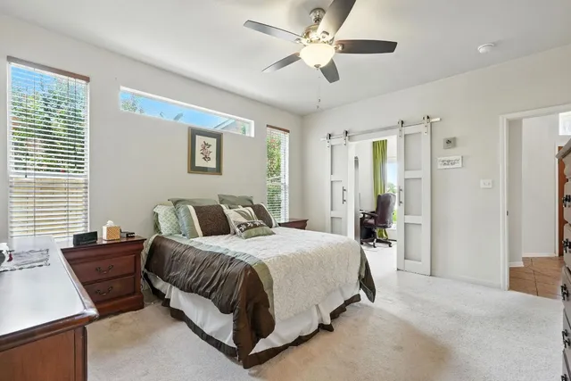 a bedroom with a bed ceiling fan and a window