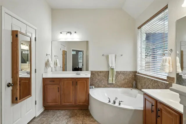 a bathroom with a granite countertop tub sink and mirror