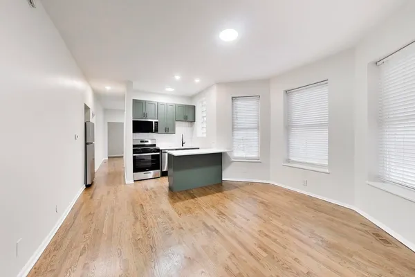 a large kitchen with a large counter top a sink stainless steel appliances and cabinets