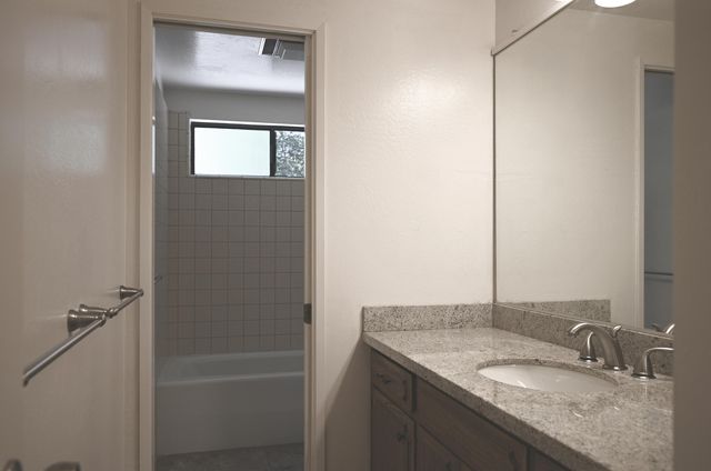 a bathroom with a granite countertop sink a mirror and a vanity
