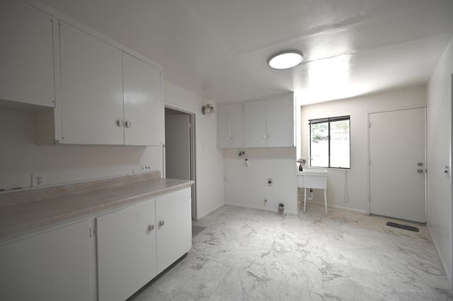 a view of a kitchen with white cabinets and a window
