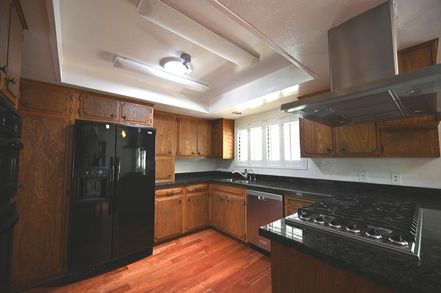 a kitchen with granite countertop a refrigerator stove and sink
