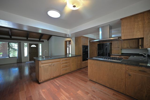 a large kitchen with stainless steel appliances granite countertop a stove and a wooden floors