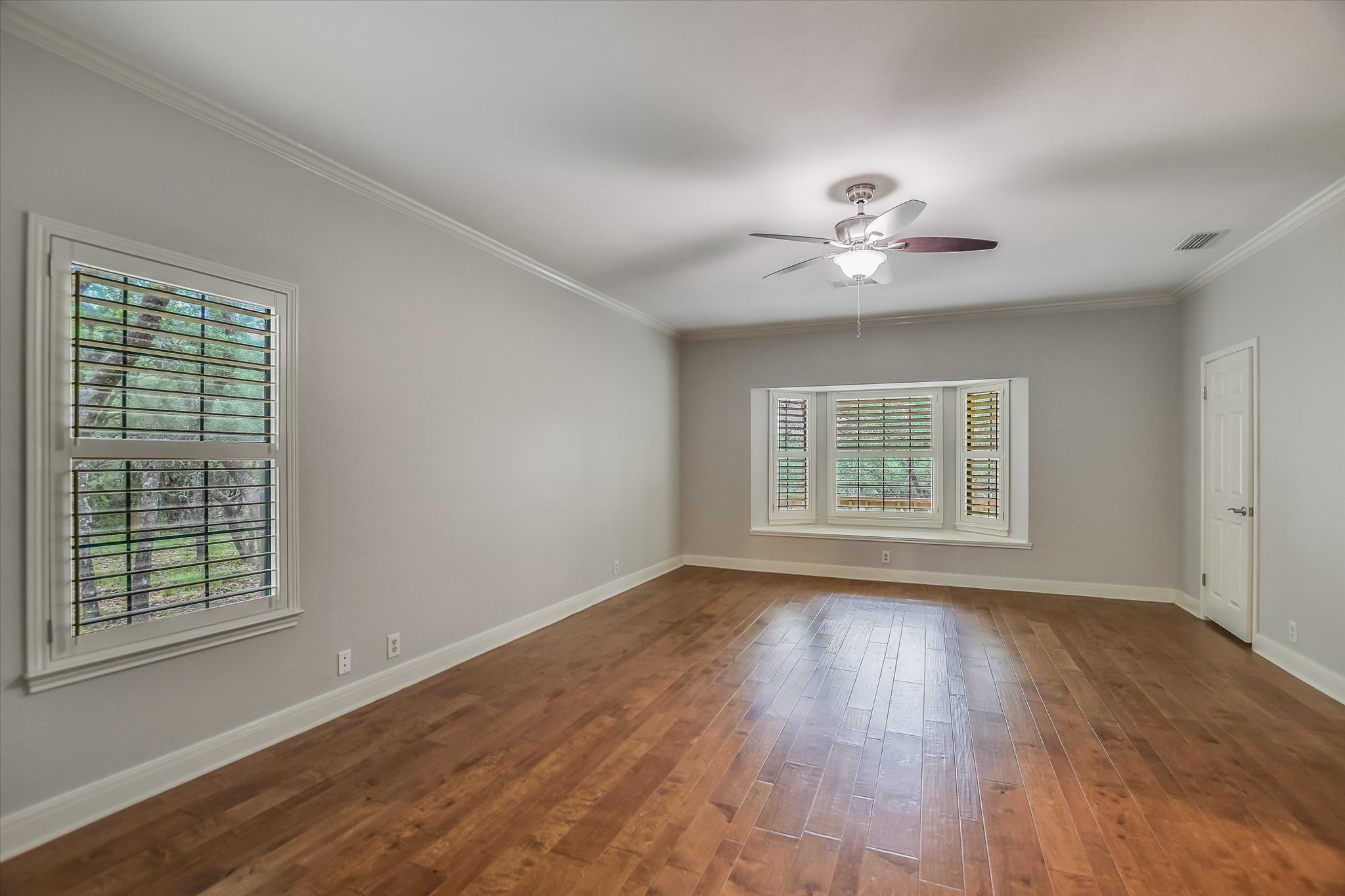 328 Fawnridge Street Georgetown, TX 78628 - Photo 13 of 33 Spacious primary bedroom with engineered wood floors, windows with shutters, ceiling fan, and dual walk-in closets.
