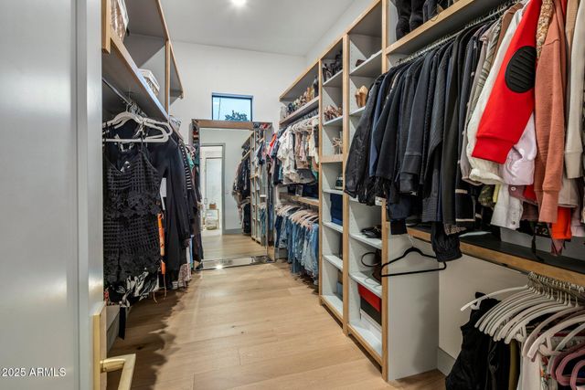 a view of walk in closet with clothes and shoes