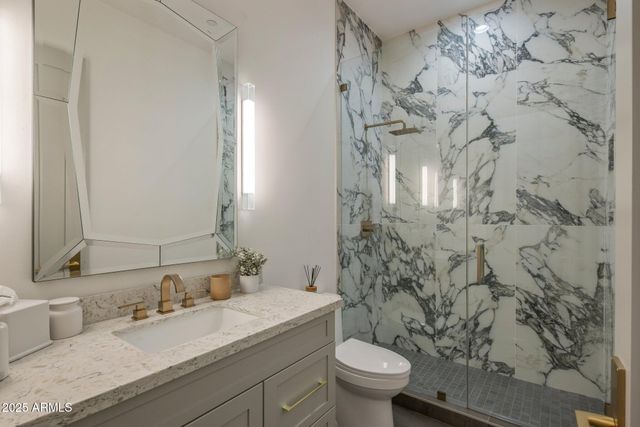 a bathroom with a granite countertop sink a toilet and a mirror
