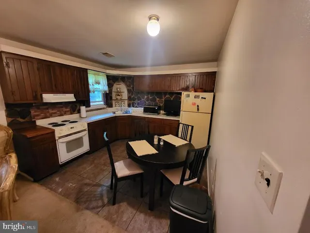 a kitchen with a dining table chairs and a refrigerator