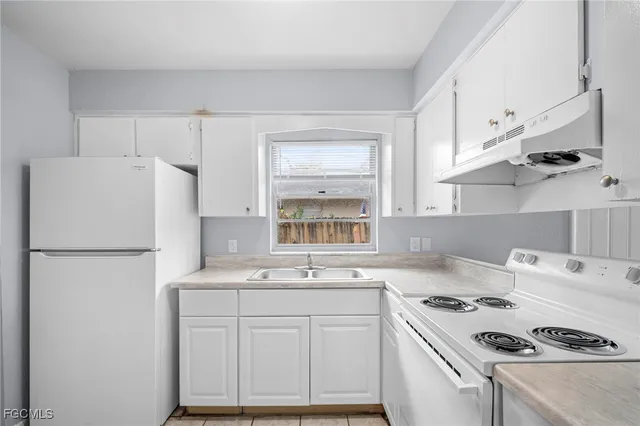 a kitchen with kitchen island a sink a stove a refrigerator and white cabinets
