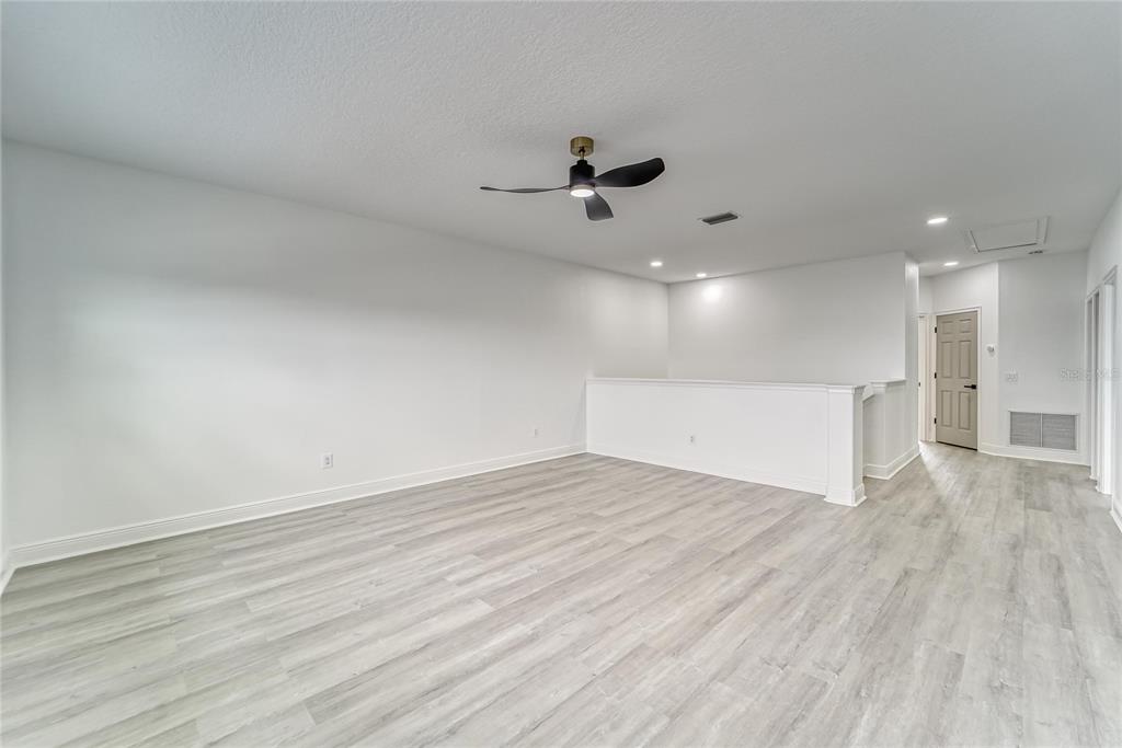 5718 Sea Turtle Place Apollo Beach, FL 33572 - Photo 29 of 81 an empty room with wooden floor a ceiling fan white walls and windows