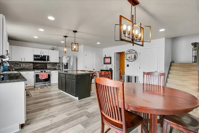 a kitchen with stainless steel appliances kitchen island granite countertop a stove a refrigerator a kitchen island a dining table and chairs with wooden floor