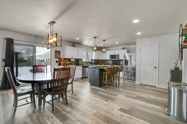 a kitchen with stainless steel appliances kitchen island granite countertop a table chairs and a refrigerator