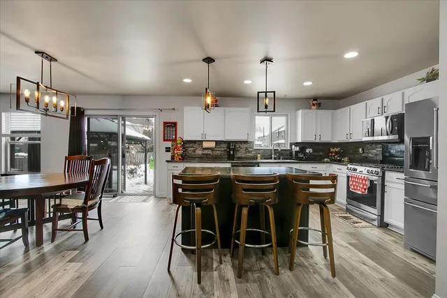 a kitchen with stainless steel appliances kitchen island granite countertop a dining table chairs and granite counter tops