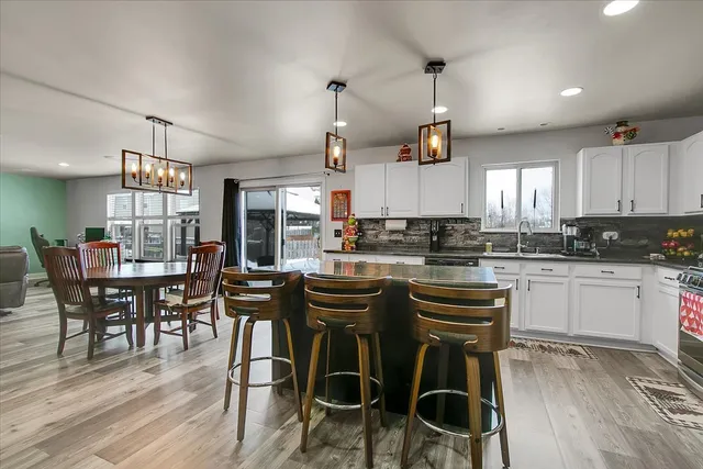 a kitchen with stainless steel appliances granite countertop wooden floor cabinets dining table and chairs