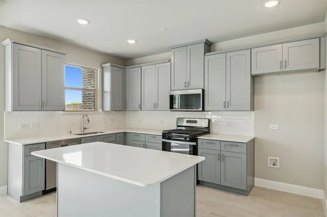 a kitchen with stainless steel appliances a sink a stove a microwave a sink a refrigerator and cabinets