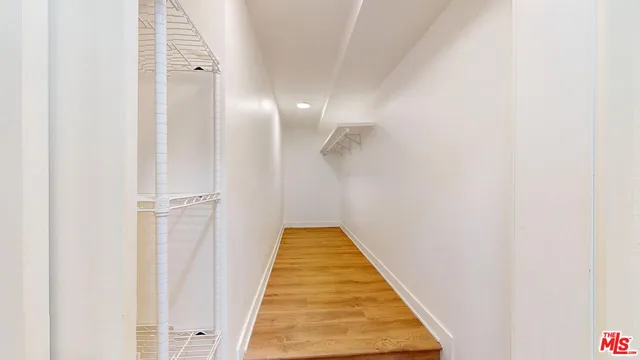 a view of a hallway with wooden floor and a bathroom