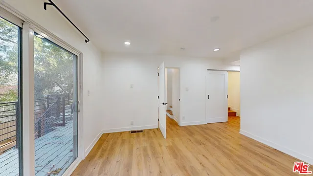 a view of empty room with wooden floor and fan