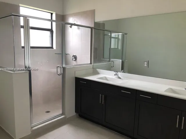 a bathroom with a double vanity sink mirror and shower