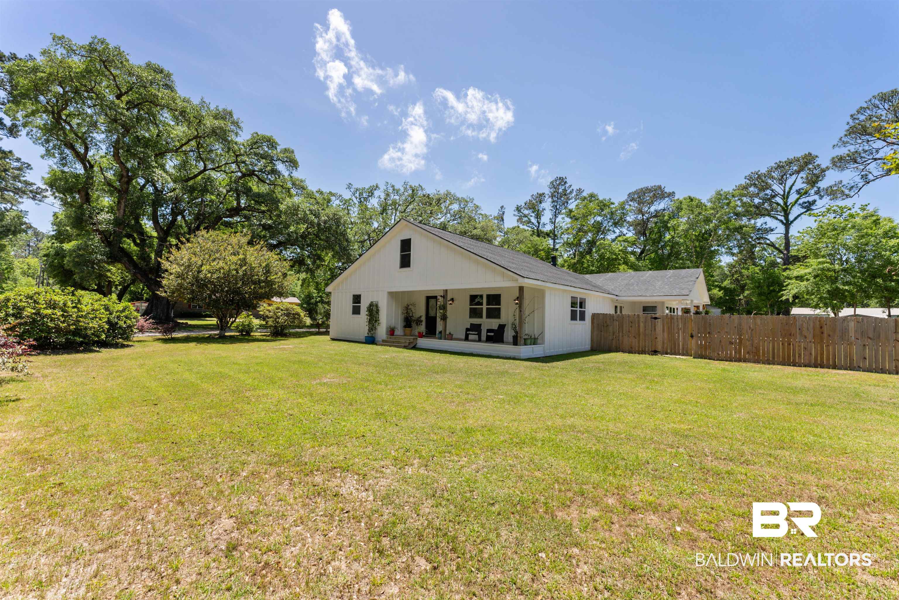 6447 Bemis Lane Bon Secour, AL 36511 - Photo 59 of 62 Expansive grassy area with mature trees and a white-sided residence featuring a covered patio and a privacy fence