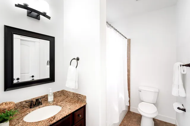 a bathroom with a granite countertop sink toilet and mirror