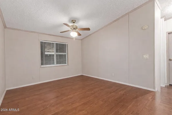a view of empty room with wooden floor and fan