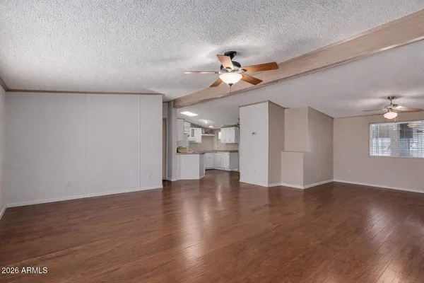 a view of an empty room with a kitchen and wooden floor