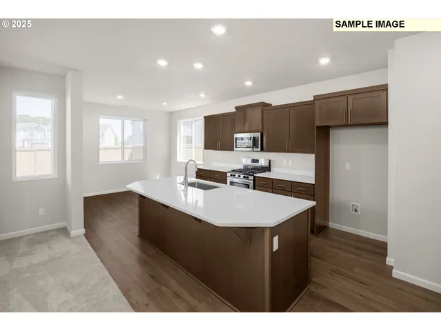 a kitchen with stainless steel appliances a sink a stove a refrigerator with wooden floor and cabinets