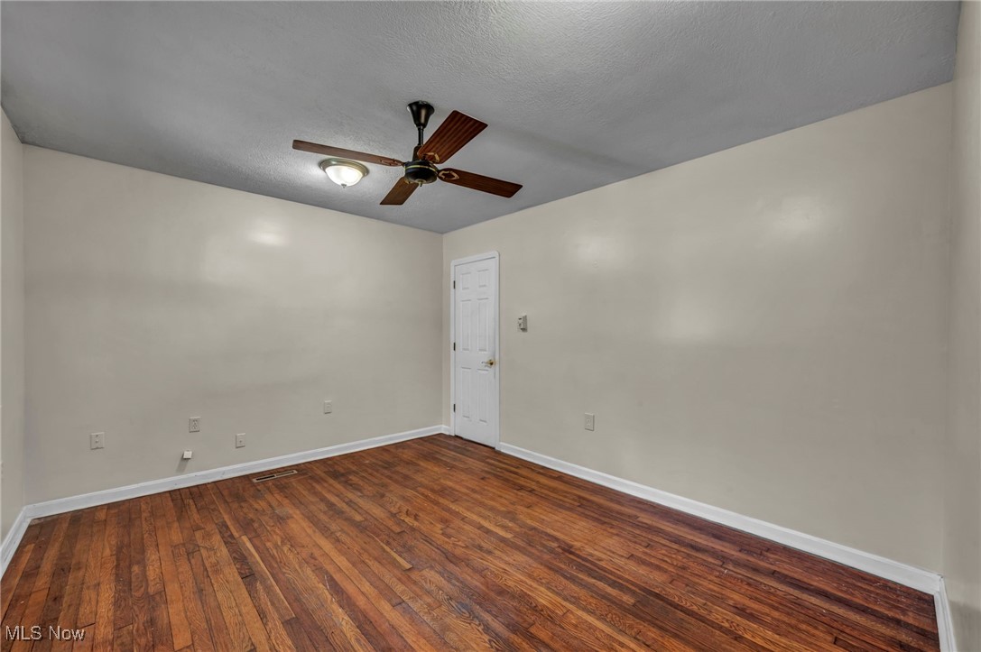 10982 Root Road Columbia Station, OH 44028 - Photo 14 of 49 Empty room with dark wood-style flooring, ceiling fan, and a textured ceiling