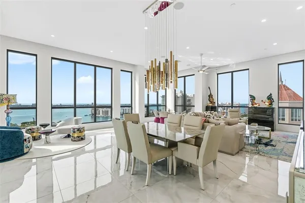 a room with lots of white furniture and a large window