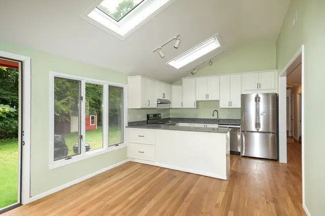a kitchen with a refrigerator a stove cabinets and wooden floor