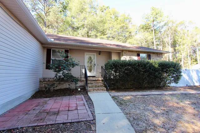 a backyard of a house with large trees and plants