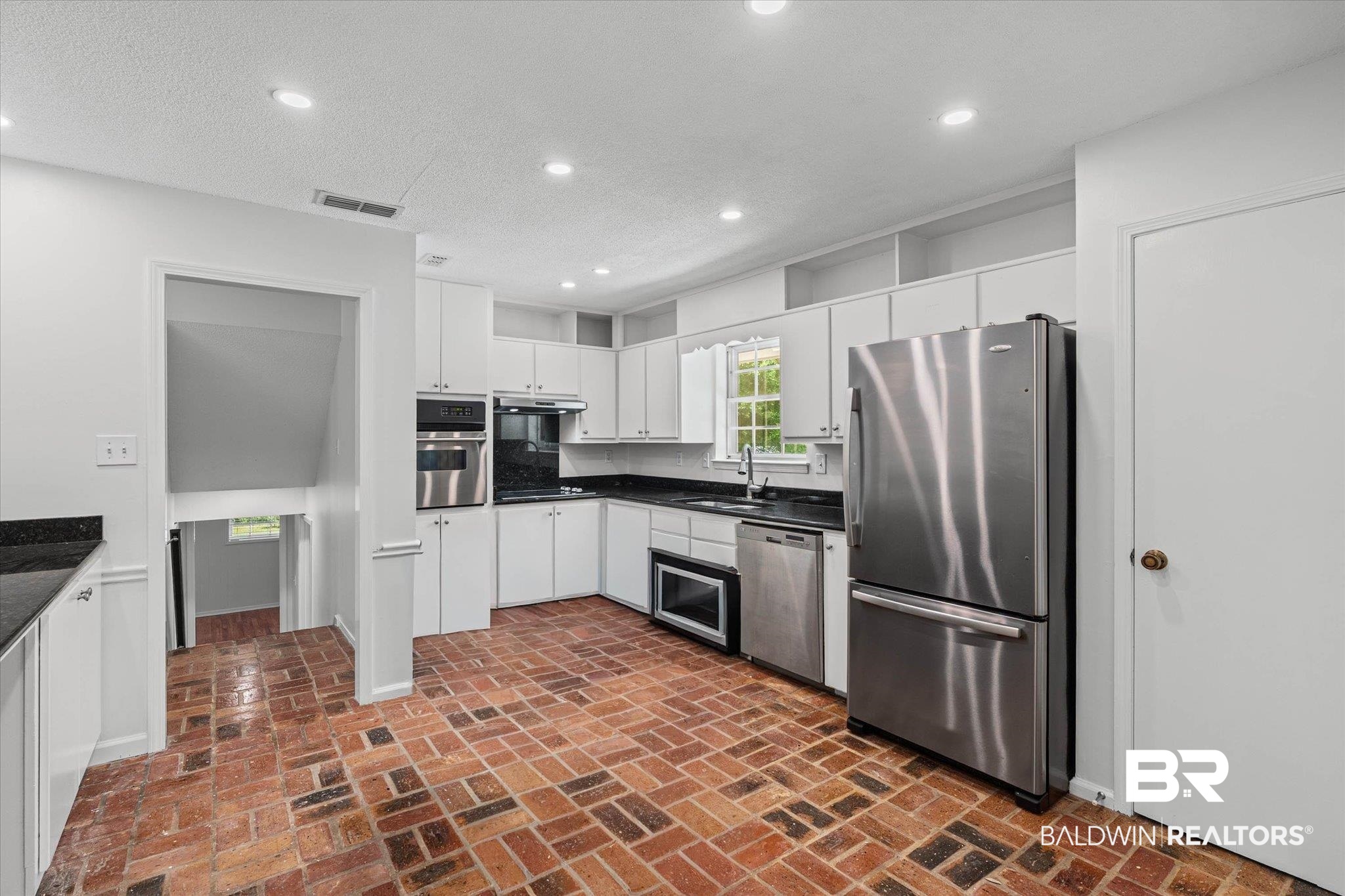 8301 Fordham Road Mobile, AL 36619 - Photo 9 of 57 Kitchen featuring brick-patterned flooring, white cabinetry, dark countertops, and stainless steel appliances