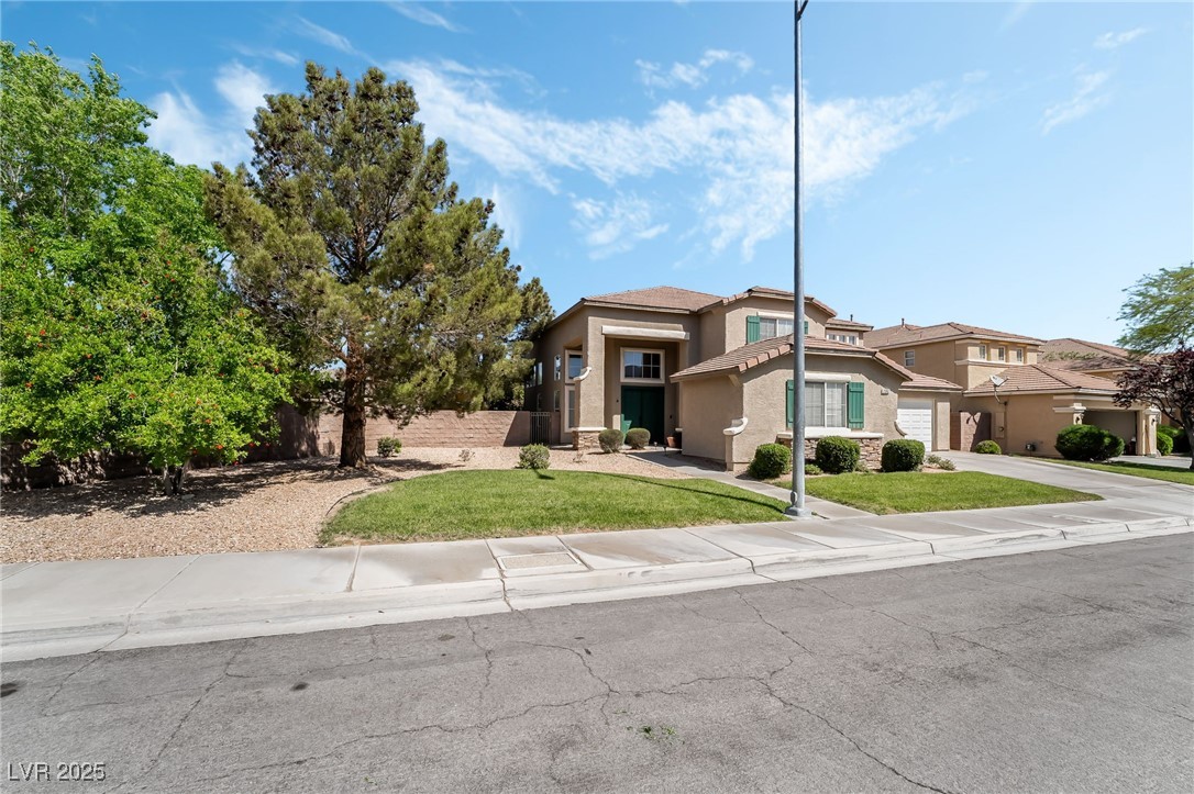 View of front of home with stucco siding, driveway, a garage, and a front yard