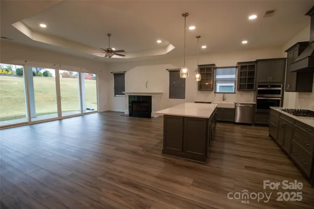 a large kitchen with kitchen island a island wooden floor and stainless steel appliances
